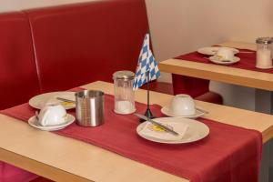 a table with a red table cloth with plates and a flag at Pension Torkel-Stube in Ingolstadt