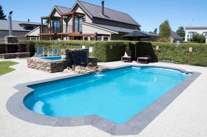 a swimming pool in front of a house at Wanaka Luxury Apartments in Wanaka