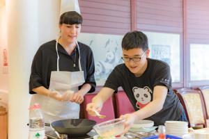 a man and a woman preparing food in a kitchen at Wenjun Courtyard Hotel ---5 mins walk from Tonghuimen metro station, near Tianfu square, close by culture park and Sichuan opera house, English speaking service, local tours in Chengdu
