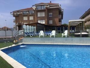 a large swimming pool with chairs and a building at Hotel Gala in Noja