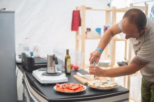 Un homme debout dans une cuisine préparant de la nourriture sur un comptoir dans l'établissement The Spot Surfcamp, à Biscarrosse