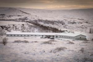 a building in a snow covered field with a mountain at Hotel Gullfoss in Haukadalur