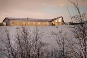 a large house in a snowy field with a building at Hotel Gullfoss in Haukadalur