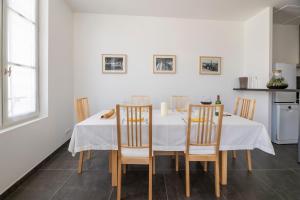 une salle à manger avec une table et des chaises blanches dans l'établissement Le 25, appartement moderne au cœur de Saint-Emilion, à Saint-Émilion