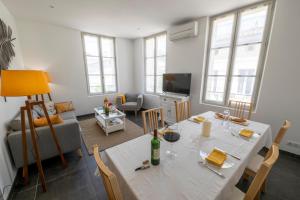 ein Wohnzimmer mit einem weißen Tisch und einer Flasche Wein in der Unterkunft Le 25, appartement moderne au cœur de Saint-Emilion in Saint-Émilion