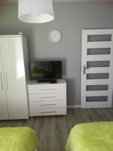 ein Schlafzimmer mit einem Flachbild-TV und einer weißen Kommode in der Unterkunft Centrum Haus in Giżycko