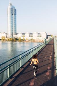 a woman walking on a bridge next to the water at harry's home hotel & apartments in Vienna