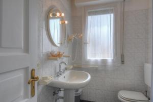 baño con lavabo y aseo y ventana en Hotel Arabesque, en Varigotti