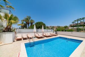 a pool on the roof of a building with lounge chairs at Baldacchino Holiday Villas in Mellieħa