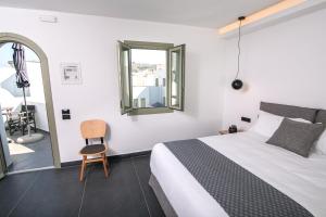 ein Schlafzimmer mit einem Bett und einem Stuhl und einem Fenster in der Unterkunft Kallos Imar Boutique Hotel in Mesariá