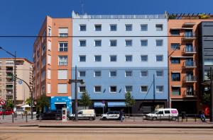 un bâtiment blanc dans une rue de la ville avec des voitures garées dans l'établissement Hotel Olympia Universidades, à Valence