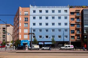 ein weißes Gebäude in einer Stadtstraße mit geparkten Autos in der Unterkunft Hotel Olympia Universidades in Valencia