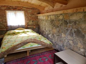 a bedroom with a bed in a stone wall at Eco Camp Dzogaska Vrela in Pljevlja