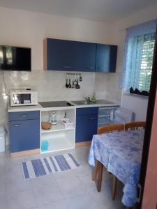 a kitchen with blue cabinets and a table in it at Apartments Juretic in Drenje