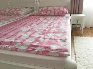 Una cama con un edredón rosa y blanco. en Balatonfenyves - Munkácsy u. 6., en Balatonfenyves