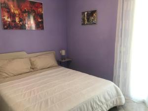 a bedroom with a white bed with purple walls at Nel cuore dell'Ossola in Pallanzeno