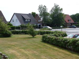 einen Hof mit einigen Büschen und Häusern und einer Straße in der Unterkunft Appartement 89 in Westerland