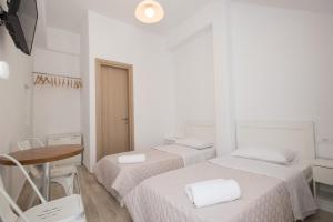 a white room with three beds and a table at Lovely Studios In Mykonos Old Town in Mýkonos City