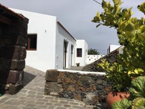 uma casa branca com uma parede de pedra e algumas plantas em Casa Viges em El Pinar del Hierro