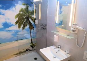 uma casa de banho com um lavatório e uma palmeira pintada na parede em BeachIN - Sport, Events, Hotel, Restaurant, Bar em Ins