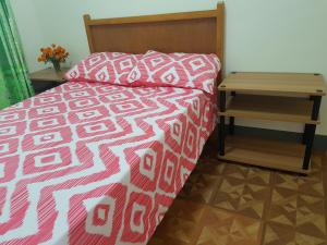 a bed with a red and white comforter and a side table at OMG Guesthouse Room for 2 in Licup
