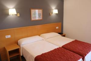 a hotel room with two beds and two lamps at Hotel Santa Faz in San Juan de Alicante