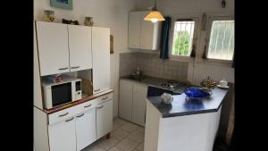 a kitchen with white cabinets and a microwave at Studio « Les pieds dans l’eau » in Martigues