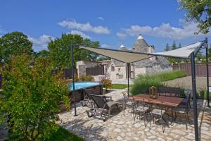 a patio with a table and chairs under a white umbrella at I trulli di Ginevra in Alberobello