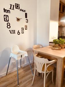 a dining room table with chairs and a clock on the wall at Apartament Batorego 713 in Gdynia