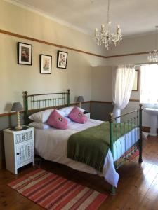 Un dormitorio con una cama con almohadas rosas y una lámpara de araña. en Apple and Rose, en Belfast