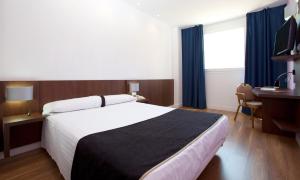 a hotel room with a bed, desk, chair and a lamp at Hotel Olympia Universidades in Valencia