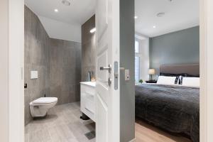 a bathroom with a bed and a toilet in a room at Barfot Apartments in Bergen