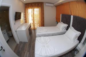 Habitación pequeña con 2 camas y TV. en Hotel Ramo Saranda en Sarandë