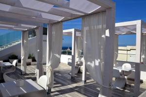 uma varanda com cortinas brancas, mesas e cadeiras em Quintessenza - Charme Rooms em Vieste