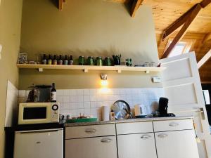 cocina con armarios blancos y microondas en Onder de Appelboom, en Garminge