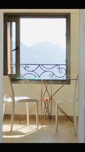 a glass table and a chair in front of a window at Lumio petite maison loft vue mer imprenable in Lumio