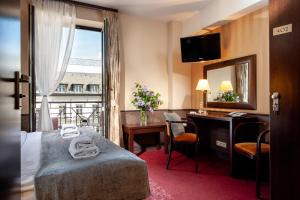 a hotel room with a bed and a desk and a window at Hotel Wielopole in Krakow