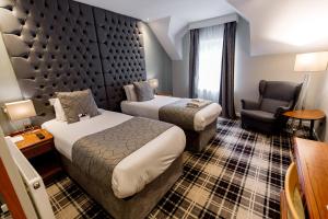 a hotel room with two beds and a chair at The Heritage Park Hotel in Pontypridd