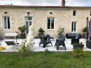 une terrasse avec des chaises et une statue en face d'un bâtiment dans l'établissement Gîtes du Perey, à Jau-Dignac-et-Loirac