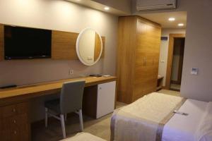 um quarto de hotel com uma cama e uma secretária com uma televisão em AKBAK OTEL em Çankırı