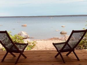 two chairs sitting on a deck looking at the water at Small Vinter Summer House in Käsmu