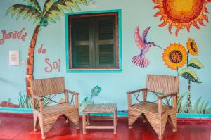 duas cadeiras em frente a uma parede com um mural em Pousada Morada do Sol em Canoa Quebrada