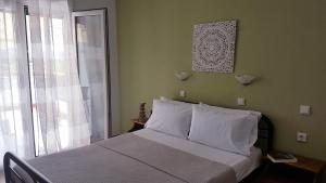 ein Schlafzimmer mit einem Bett mit weißen Kissen und einem Fenster in der Unterkunft Lina Studios in Potos
