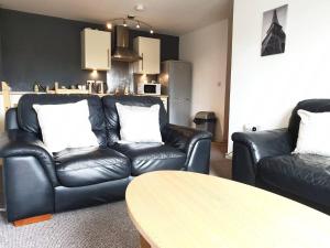 a living room with two black leather couches and a table at 2 Bedroom Apartment Warrington Free Parking Hosted By Seren Property in Warrington