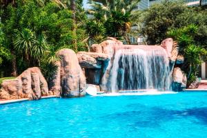 a pool of water with a waterfall next to it at Ona Jardines Paraisol in Salou