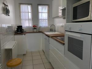 Una cocina blanca con fregadero y microondas. en La terrasse honfleuraise, en Honfleur
