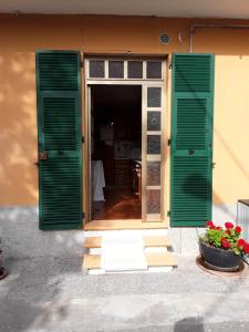 une porte ouverte avec des volets verts et un pot de fleurs dans l'établissement OLGATAN, à Deiva Marina