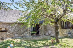 ein Steinhaus mit einem Baum im Hof in der Unterkunft Casa Parrot by SeaMount Rentals in Gessa