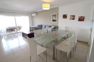 a dining room with a glass table and white chairs at Lotus Villa V5 com piscina comum - Boliqueime, Algarve in Boliqueime