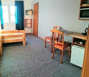 ダルウォボにあるPokoje Goscinneのデスク、ベッド、テーブル、椅子が備わる客室です。